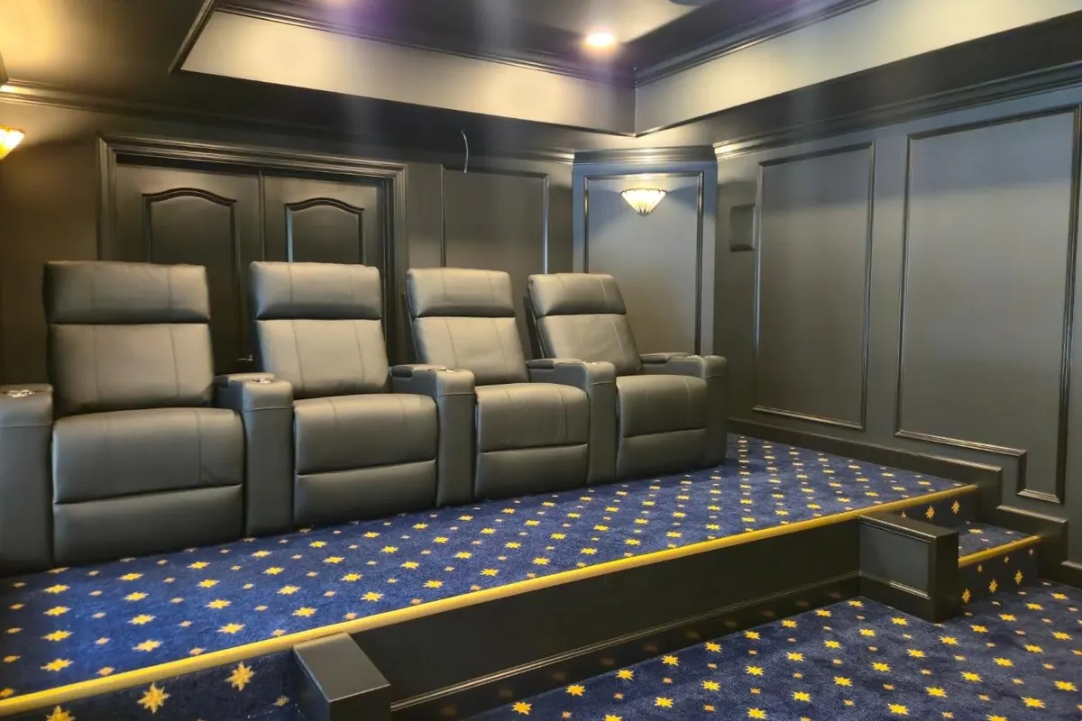 Finished basement home theater with tiered recliners and dark paneled walls