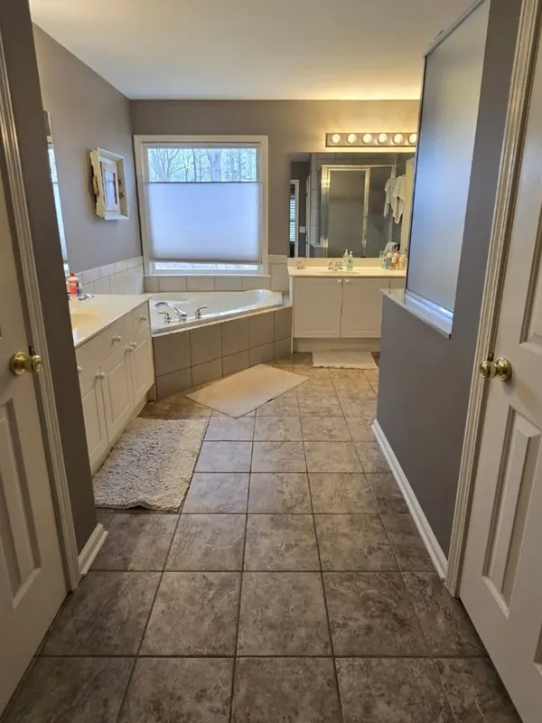 Primary bathroom before the remodel, with a corner tub and brown floor tile